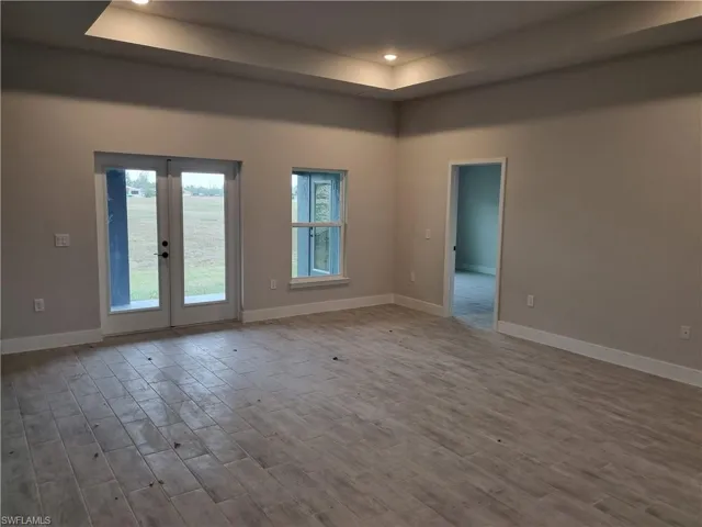 Spare room with wood finished floors, recessed lighting, a raised ceiling, and french doors