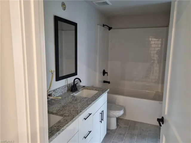 Bathroom with double vanity, shower / tub combination, and wood tiled floors