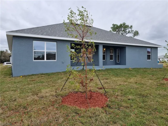 Back of house with a patio, stucco siding, a yard, and roof with shingles