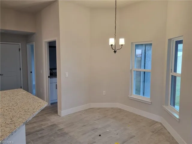 Unfurnished dining area featuring wood tiled floors and a chandelier