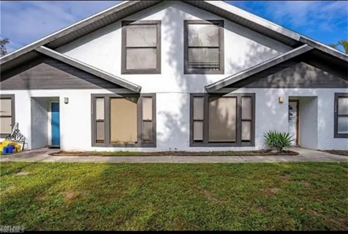 Rear view of house featuring stucco siding and a lawn
