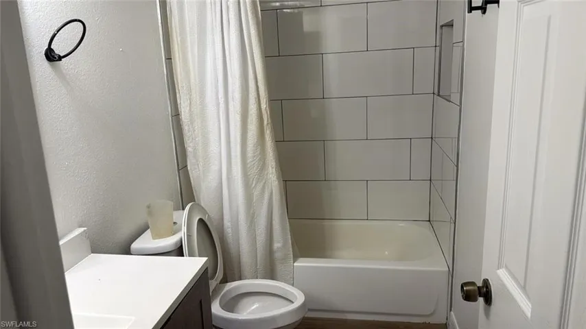 Bathroom featuring vanity, shower / tub combo, and a textured wall