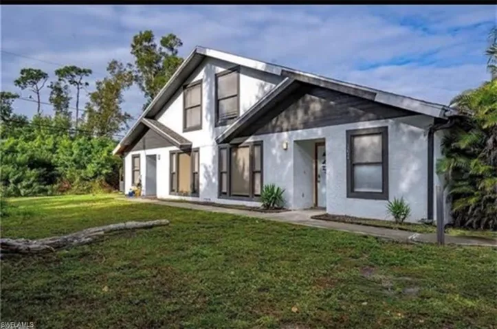 Rear view of house with a lawn and stucco siding
