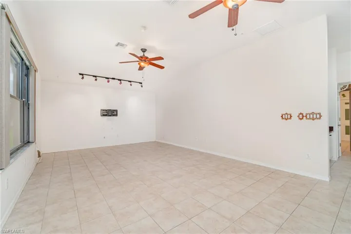 Spare room with ceiling fan, track lighting, and light tile patterned floors