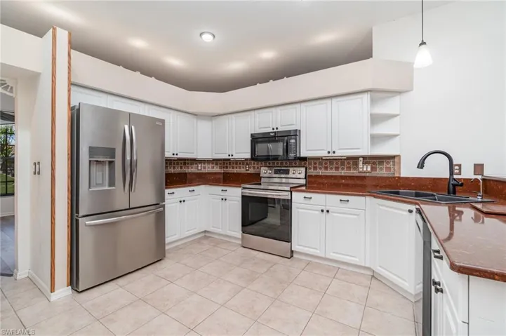 Kitchen featuring stainless steel appliances, white cabinetry, open shelves, tasteful backsplash, and a peninsula