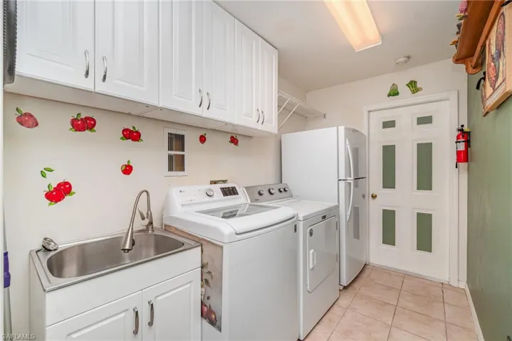 Laundry area with cabinet space, separate washer and dryer, and light tile patterned floors