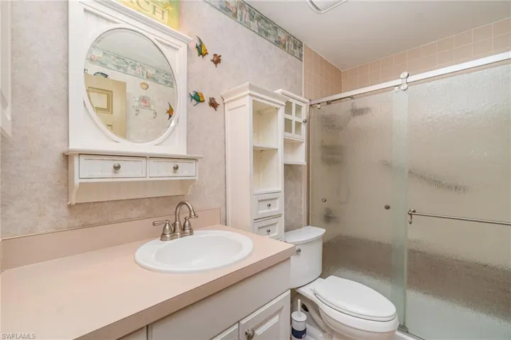 Full bath featuring wallpapered walls, vanity, and a shower stall