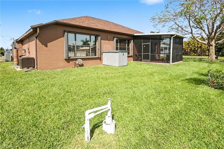 Back of house with a lawn, stucco siding, and a sunroom