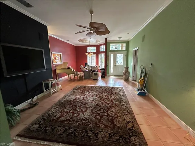 Foyer entrance with crown molding, light tile patterned floors, and ceiling fan