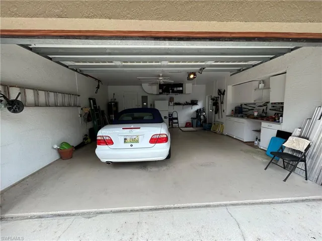 Garage with a textured wall, freestanding refrigerator, and water heater