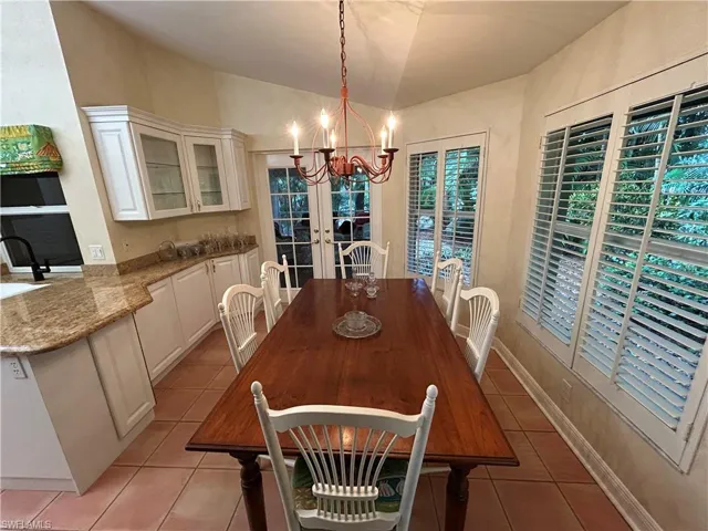 Dining room with light tile patterned floors, a chandelier, and lofted ceiling