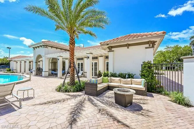Rear view of house featuring a patio, fence, a fenced in pool, stucco siding, and an outdoor living space with a fire pit