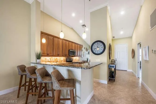 Kitchen featuring a breakfast bar, brown cabinetry, stainless steel appliances, and dark stone countertops