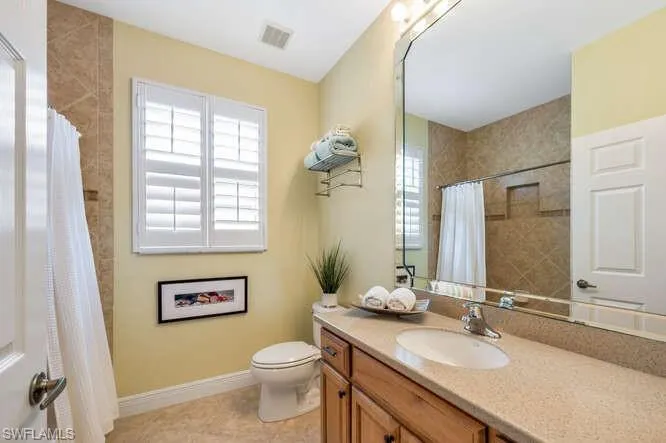 Bathroom featuring visible vents, toilet, vanity, baseboards, and tile patterned floors