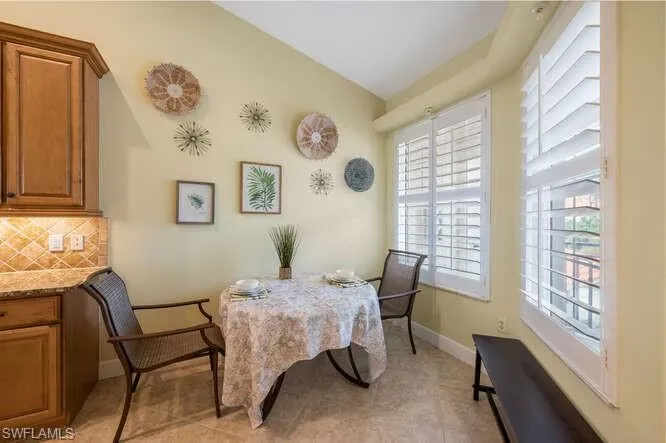 Dining area featuring light tile patterned flooring, vaulted ceiling, and baseboards