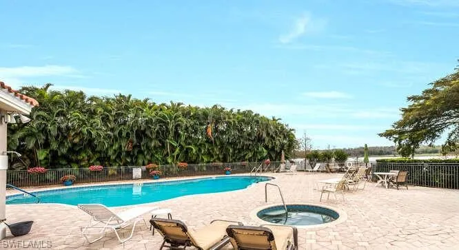 Community pool with fence, a community hot tub, and a patio