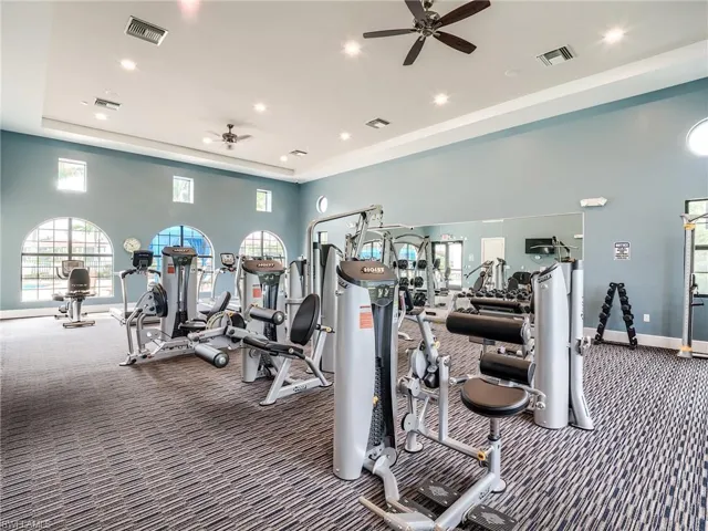 Exercise room with carpet flooring, a high ceiling, and ceiling fan