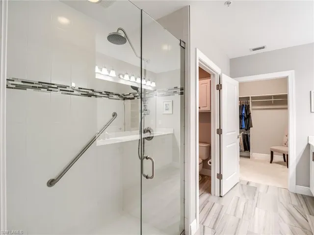 Bathroom featuring a shower with door, sink, tile flooring, and toilet
