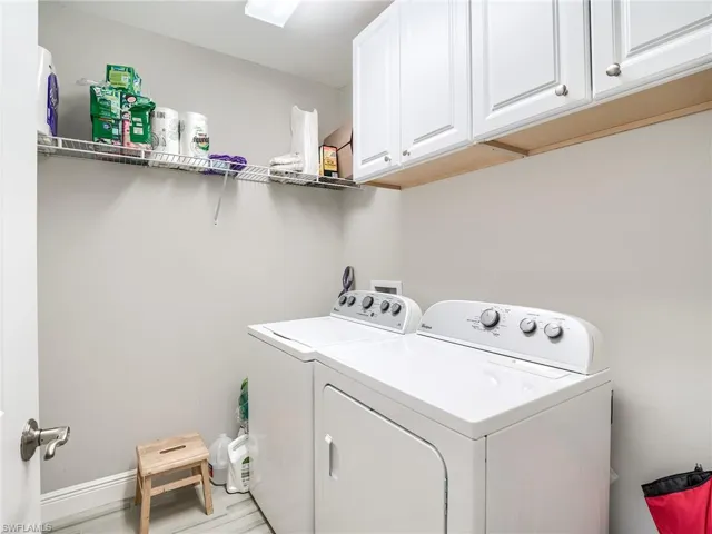 Laundry area with washer and clothes dryer, cabinets, light hardwood / wood-style flooring, and hookup for a washing machine
