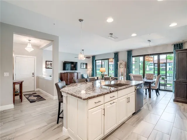 Kitchen featuring decorative light fixtures, plenty of natural light, and a center island with sink