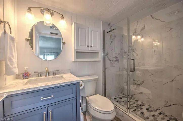 Bathroom with vanity, a marble finish shower, and a textured ceiling