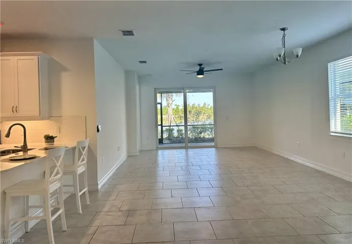Dining space with plenty of natural light, a ceiling fan, light tile patterned floors, and a chandelier