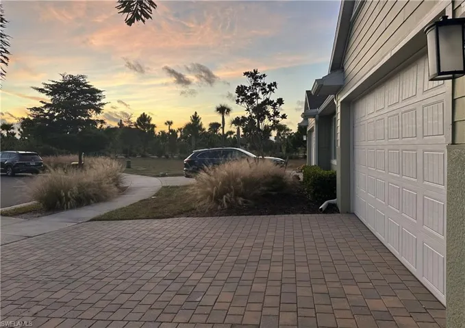 Patio terrace at dusk featuring a garage and decorative driveway