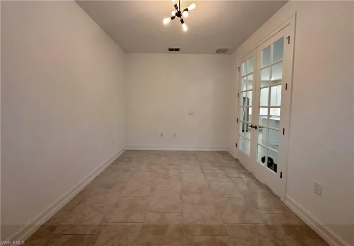 Unfurnished room with french doors, a chandelier, and light tile patterned floors