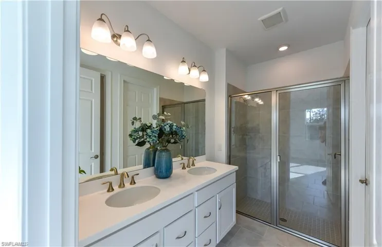 Full bathroom featuring double vanity, a shower stall, light tile patterned floors, and recessed lighting