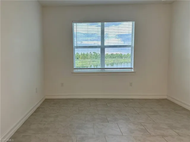 Empty room featuring baseboards and light tile patterned floors