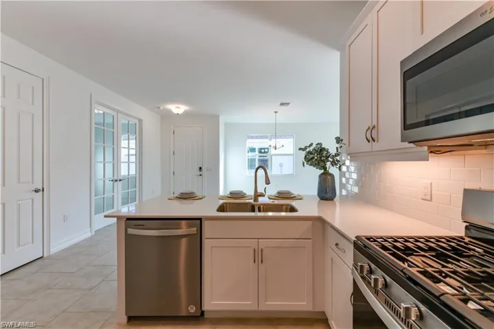 Kitchen with appliances with stainless steel finishes, a peninsula, decorative light fixtures, and healthy amount of natural light