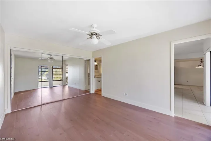 Unfurnished bedroom featuring a closet, wood finished floors, ceiling fan, and ensuite bath