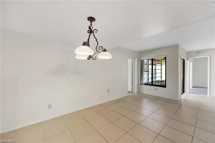Empty room with light tile patterned flooring and a chandelier