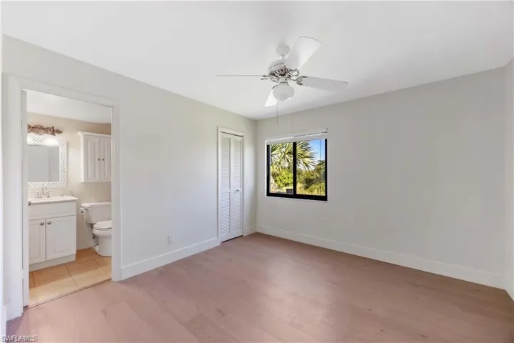 Unfurnished bedroom featuring light wood-style flooring, ceiling fan, a closet, and ensuite bathroom