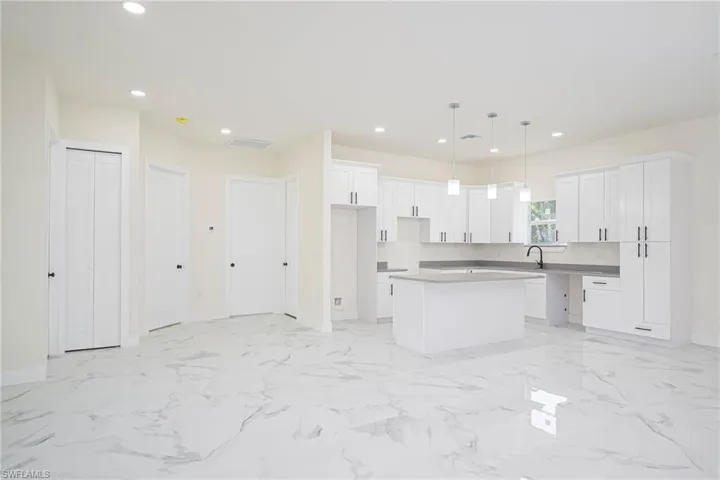 Kitchen featuring white cabinets, sink, decorative light fixtures, and a kitchen island