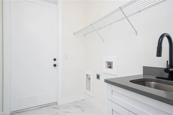 Laundry area with electric dryer hookup, washer hookup, cabinets, and sink