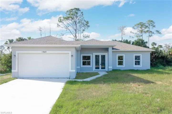 Ranch-style home featuring a garage and a front lawn