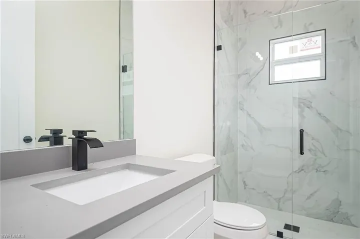 Bathroom featuring toilet, vanity, and walk in shower
