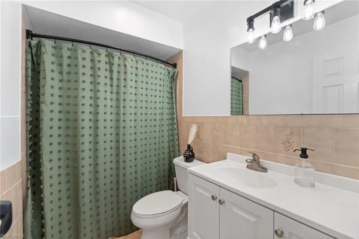 Full bathroom with tile walls, vanity, and a shower