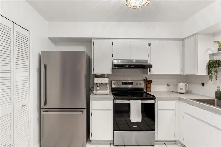 Kitchen featuring appliances with stainless steel finishes, light countertops, backsplash