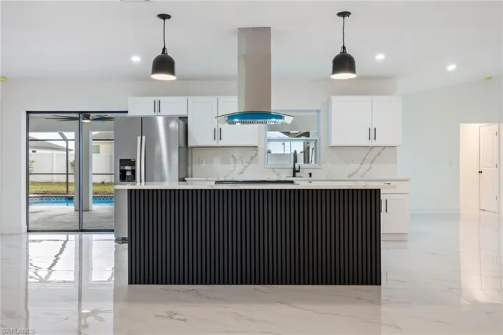 Kitchen with white cabinetry, light marble finish floors, island range hood, backsplash, and pendant lighting