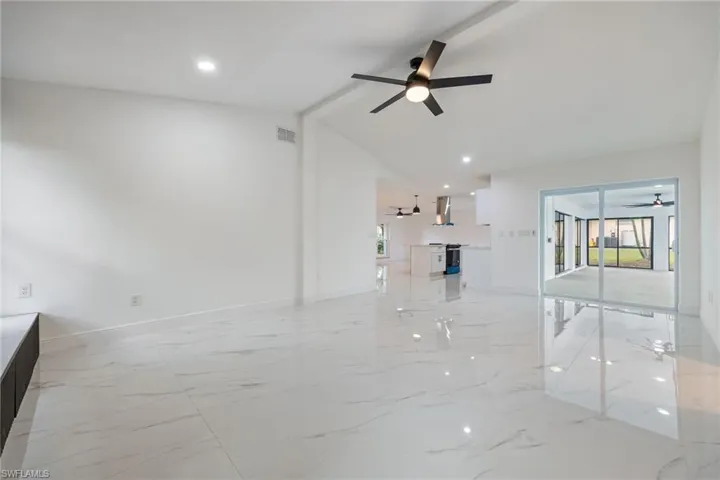 Unfurnished living room featuring light marble finish flooring, ceiling fan, and recessed lighting