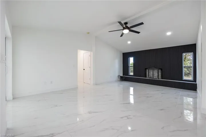 Unfurnished living room featuring light marble finish flooring, vaulted ceiling, a ceiling fan, and recessed lighting