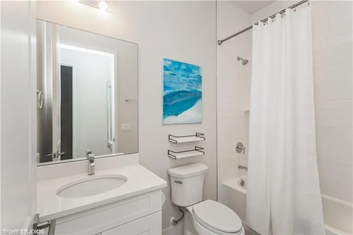 Bathroom with shower / bathtub combination with curtain, toilet, and vanity