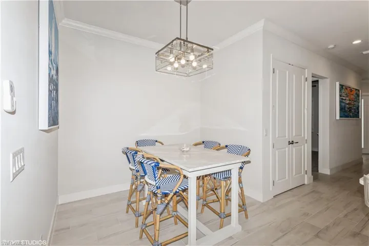 Dining space with baseboards, ornamental molding, a chandelier, light wood-type flooring, and recessed lighting