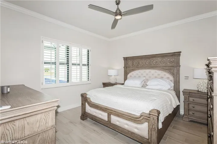 Bedroom with baseboards, crown molding, a ceiling fan, and wood finish floors