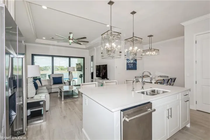 Kitchen featuring a sink, appliances with stainless steel finishes, open floor plan, an island with sink, and light countertops