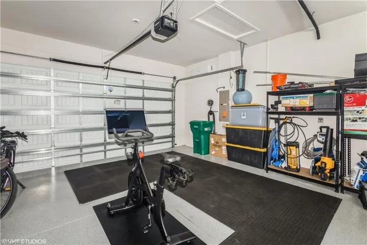 Exercise area with electric panel, a garage, and attic access