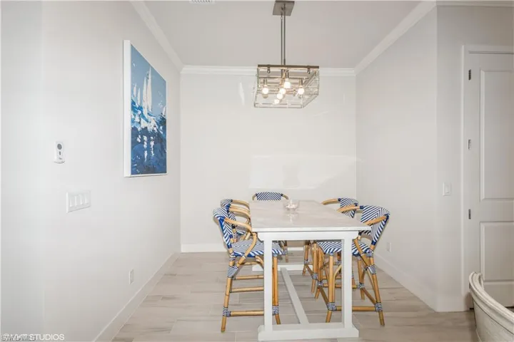 Dining room with ornamental molding, baseboards, a chandelier, and light wood-style flooring