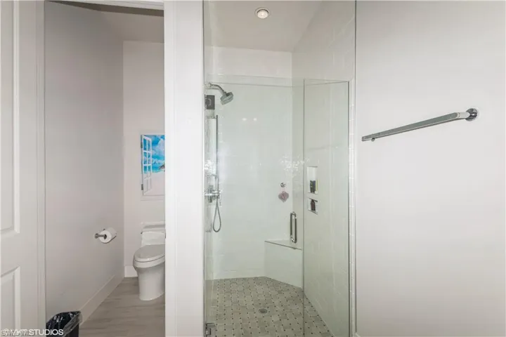 Bathroom with a shower stall, toilet, and baseboards